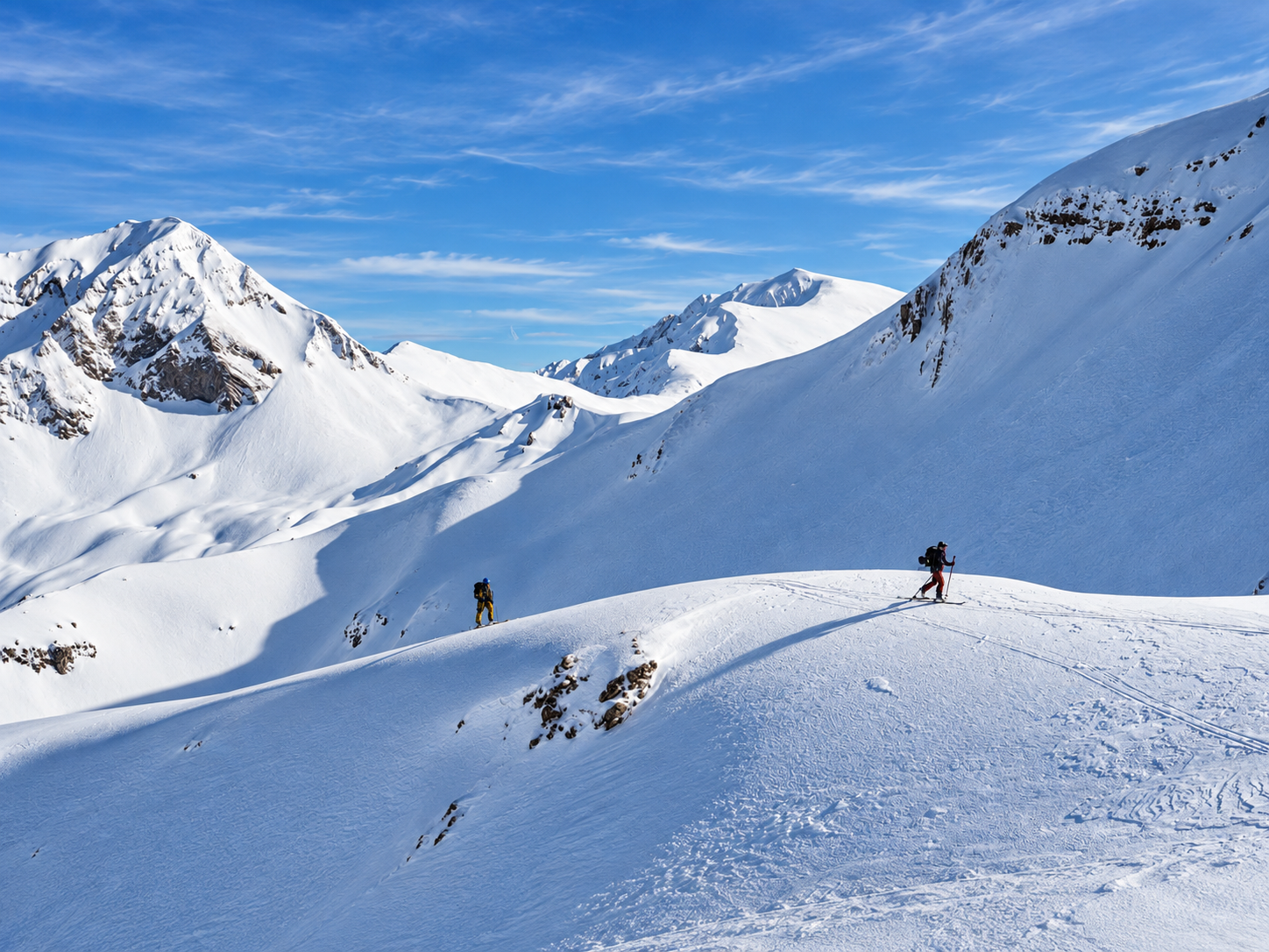 Deux skieurs de randonnée sur une crête enneigée, grand paysage de montagnes, lors d'une itinérance à ski en Grèce.